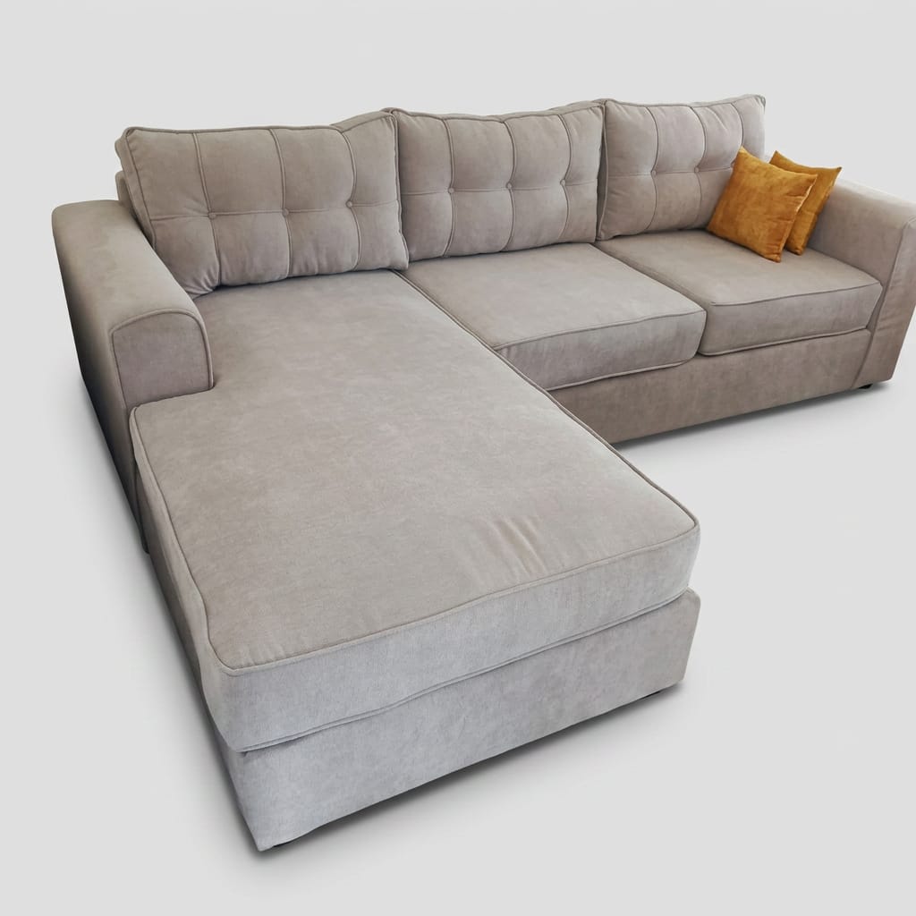 Stone grey button-tufted L-shape sectional with chaise and amber accent pillows