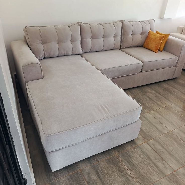 Dove grey tufted L-shape sectional with extended chaise and amber accent pillows